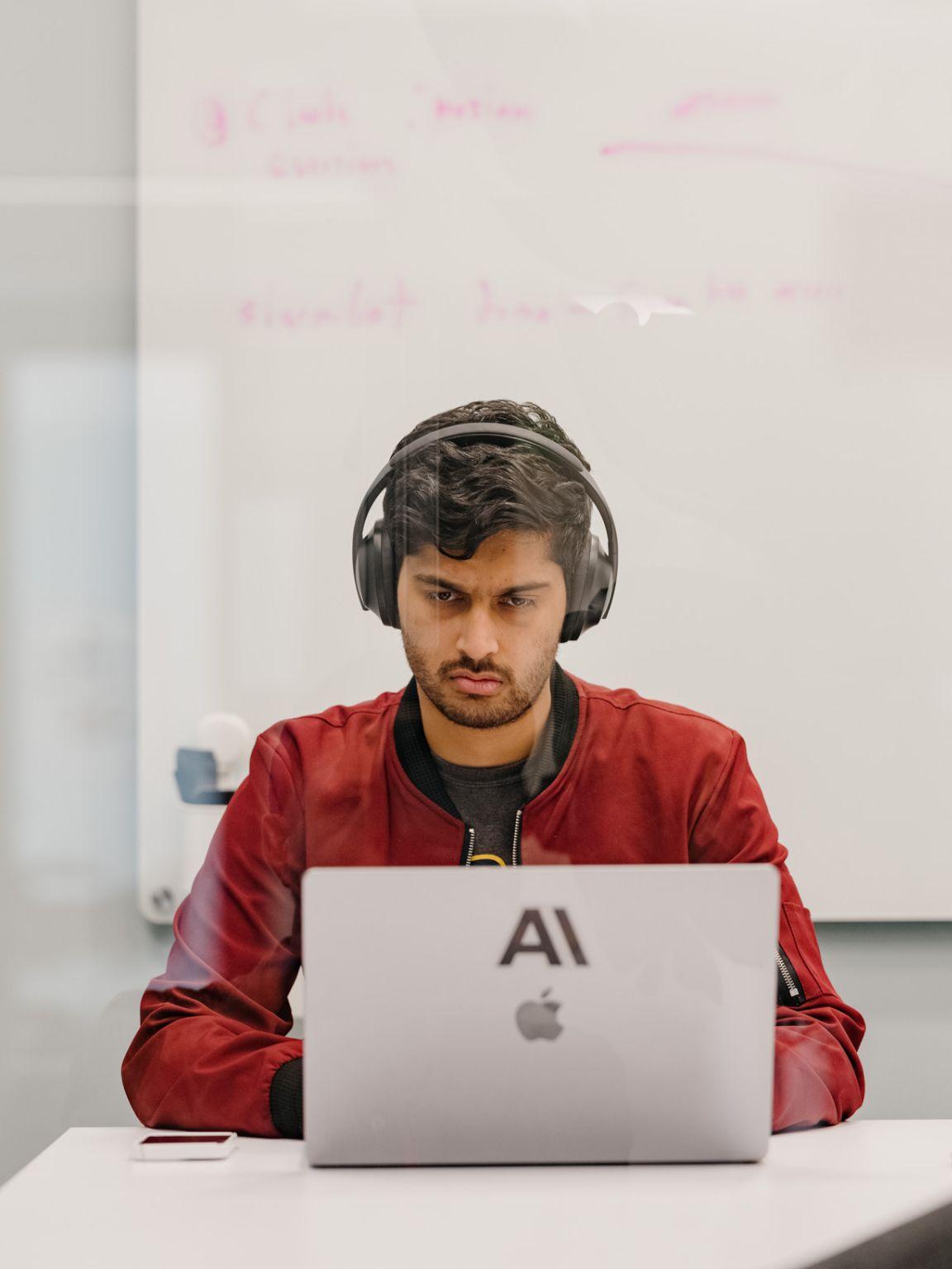 A person working on a laptop and wearing headphones